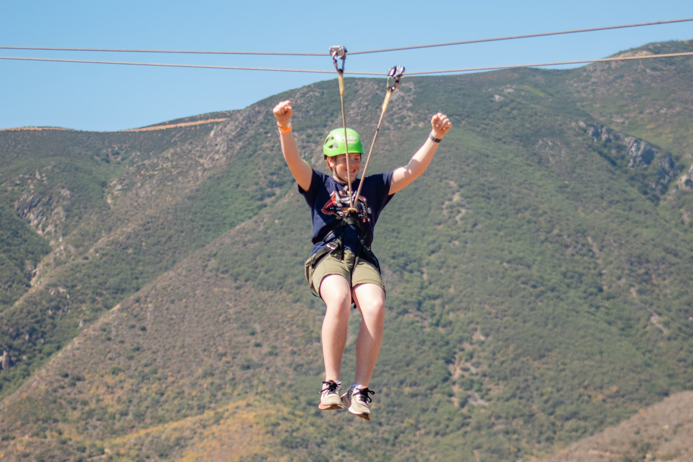 Visitante celebrando en la tirolesa sobre las montañas de Ensenada